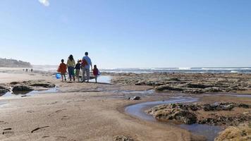 Family walking on beach with tide pools video