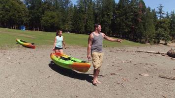 Couple carry kayak to lake video