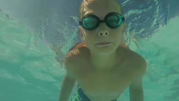 Young boy swimming in pool underwater, POV video