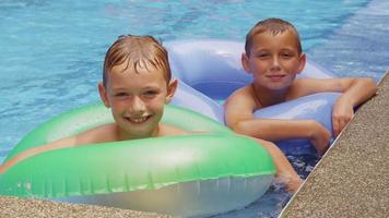 Two boys in pool with inner tubes. video