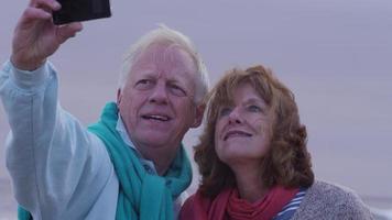 coppia di anziani che si fa un selfie sulla spiaggia