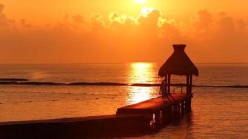 Mujer camina por el muelle durante la puesta de sol en el resort tropical video