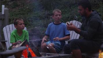 familie marshmallows roosteren bij buitenvuur. video