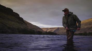 Hombre pescando con mosca en el hermoso río al amanecer. video