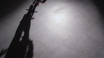 BMX rider doing tricks in dark warehouse.