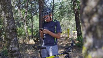 Ciclista de montaña se toma un descanso para revisar el teléfono celular video