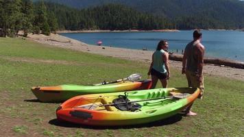 Couple carry kayaks to lake video