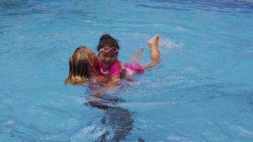 madre e hija jugando en la piscina. video