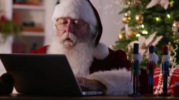 Santa Claus in workshop using laptop computer video
