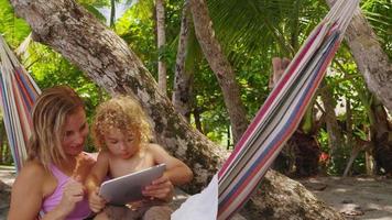 Mother and son in hammock using digital tablet video