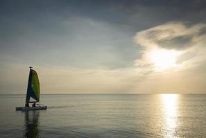 Velero en el mar durante la puesta de sol en la costa de Phuket, Tailandia foto