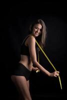 Beautiful young woman measuring her figure size with tape measure. photo