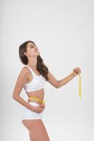 Beautiful young woman measuring her figure size with tape measure. photo