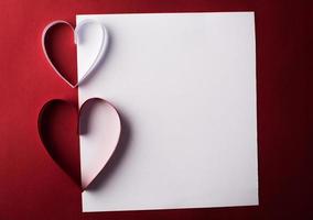 papel de corazón rojo y en blanco con tarjeta de nota sobre fondo rojo. foto