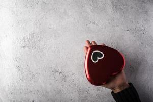 Top view Hand holding Red heart on wall background. photo