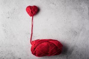 Red yarn heart shaped on the wall background. photo