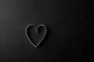 papel en forma de corazón blanco en la sombra sobre fondo negro.