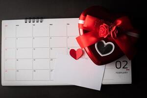 corazón rojo el 14 de febrero en el calendario con forma de corazón. caja de regalo. foto