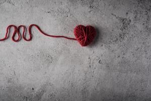 Red yarn heart shaped on the wall background. photo