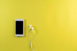 Top view cell phone and earphone on white desk. photo