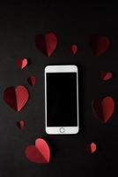 Heart and phone on black wall background. photo