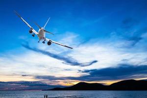 Commercial airplane flying above the sea at sunset photo