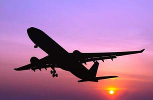 Silhouetted commercial airplane flying at sunset photo