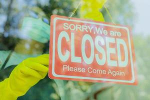 The shop owner hangs a sign to close the business in front photo