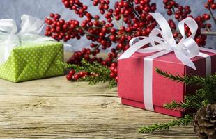 Christmas decoration of red gift box and red winterberry on old wood photo