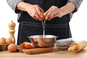 Woman hands to separate egg white and yolks with egg shells photo