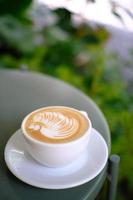 Taza de café con latte art en forma de cisne sobre la mesa de metal foto