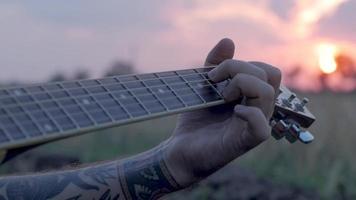 El hombre toca la guitarra acústica en los campos de verano video