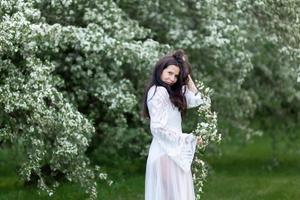 Retrato de mujer joven en el parque en las ramas florecientes foto