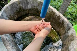 Woman washing her hands with water outdoor at a public faucet photo