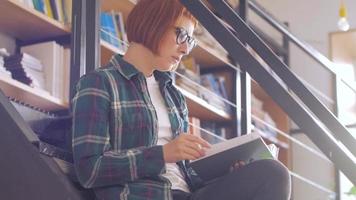 jeune femme lit un livre dans la bibliothèque video