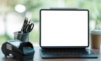 Laptop blank screen with EDC machine on a table in a coffee shop photo