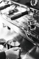 Making espresso coffee BW black and white close up detail with modern cafe machine and glasses photo