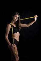 Beautiful young woman measuring her figure size with tape measure. photo