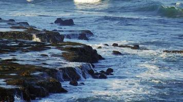 olas de mar aplastar rocas en una orilla del mar. video