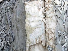 Mountain rock with gray, white, brown color stones in vertical layer photo