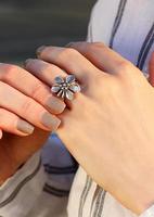 Flower form silver ring on a finger. Interesting jewelry design photo