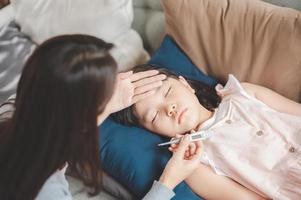 Hija de niña asiática enferma durmiendo en el sofá foto