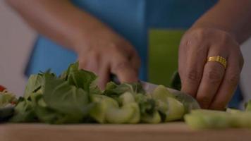 mujer preparando baby bok choy en tabla de cortar para alimentos saludables. video