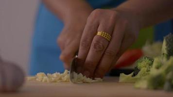 mujer cortando ajo en la tabla de cortar para cocinar comida tailandesa. video