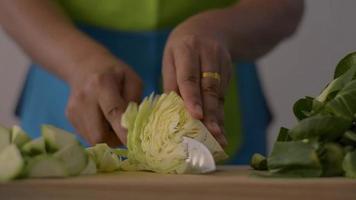kvinna som skär kål för hälsosam mat i köket. video