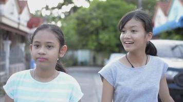 portret van Aziatische schattige meisjes die samen gelukkig op het voetpad lopen. video