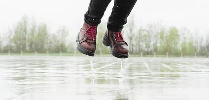 Woman playing in the rain, jumping in puddles with splashes photo