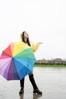 Beautiful brunette woman holding colorful umbrella out in the rain photo