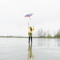 Beautiful brunette woman holding colorful umbrella out in the rain photo