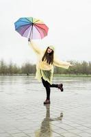 Beautiful brunette woman holding colorful umbrella out in the rain photo